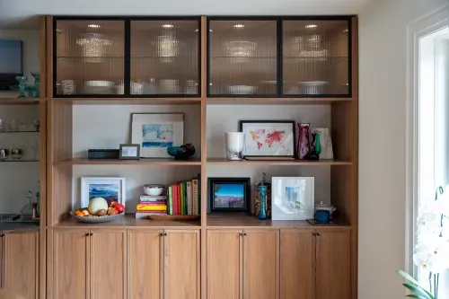 Wooden kitchen cabinetry along back wall, holds decorative objects and glassware
