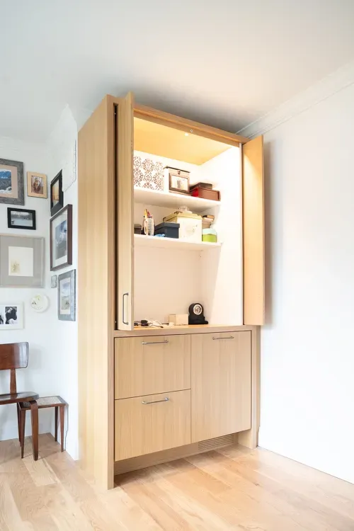 Wooden cabinet against wall with doors open to reveal storage