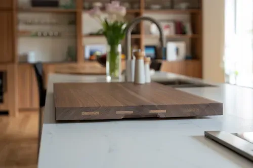 Wooden cutting board on kitchen countertop in foreground, wooden cabinetry along back wall