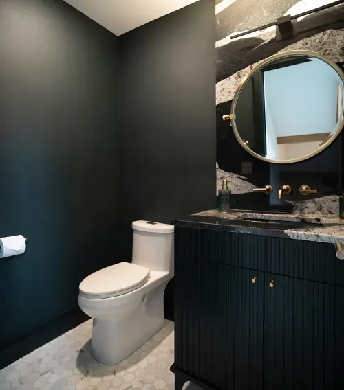 Dramatic powder room with black walls and cabinetry, gold mirror and accents
