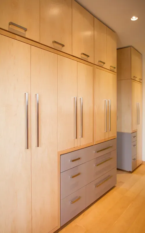 Wooden floor-to-ceiling wardrobe built in along bedroom wall