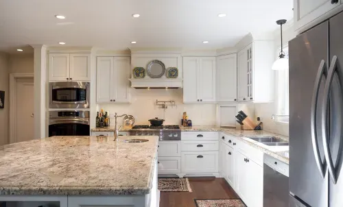 Full view of white kitchen cabinets and large marble island