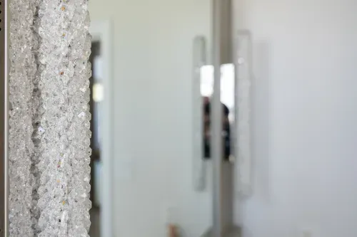 Close up of textured glass sconces on bathroom mirror
