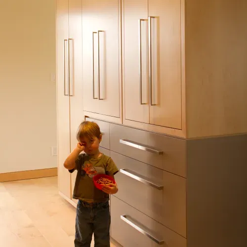 Little boy standing in front of wooden cabinets