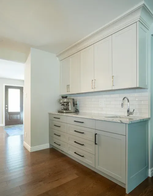 Teal and white cabinetry along wall with drink station and sink