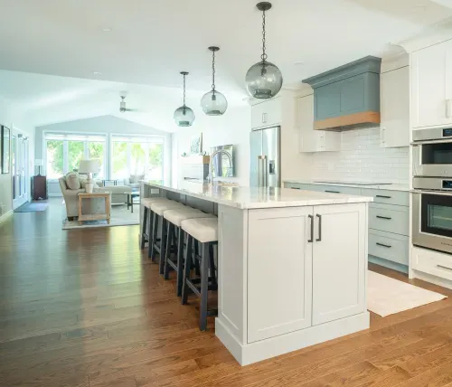 White and teal kitchen cabinets with centre island and hanging pendant lights