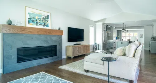 Great room with stone fireplace, wooden mantle and hardwood floors