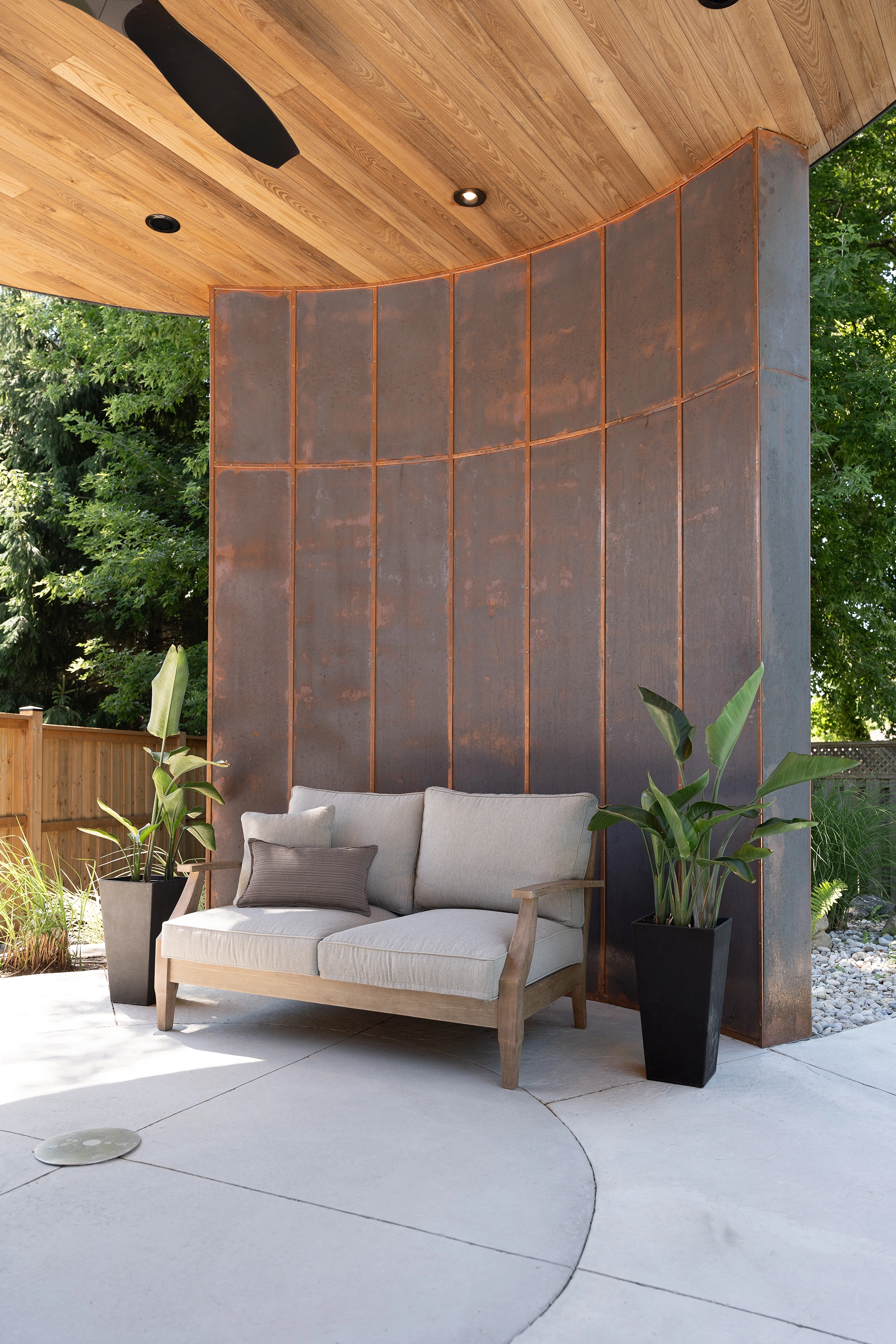 Beachy outdoor seating placed in front of copper accent wall in open-air rotunda