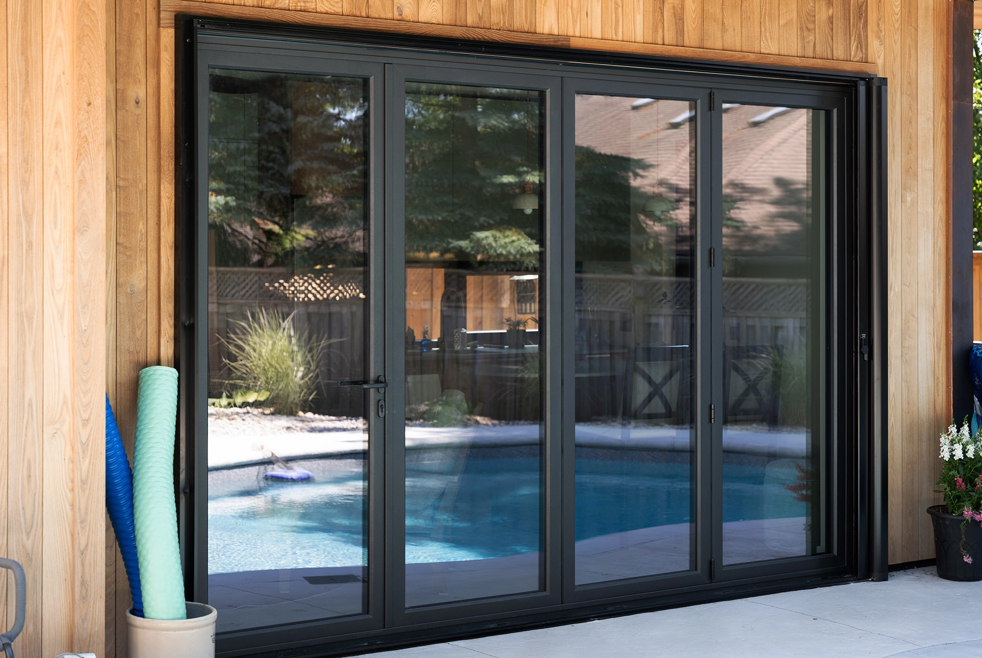 Four-panel folding glass door leading into poolhouse