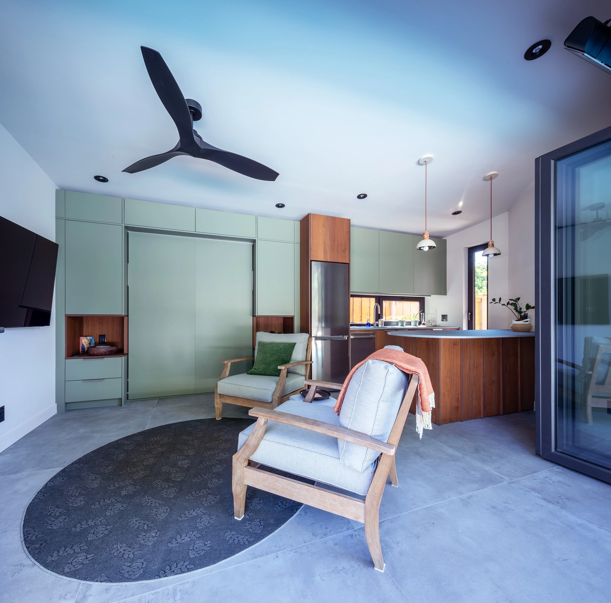 Poolhouse sitting area with beachy armchairs and green panelled walls in background