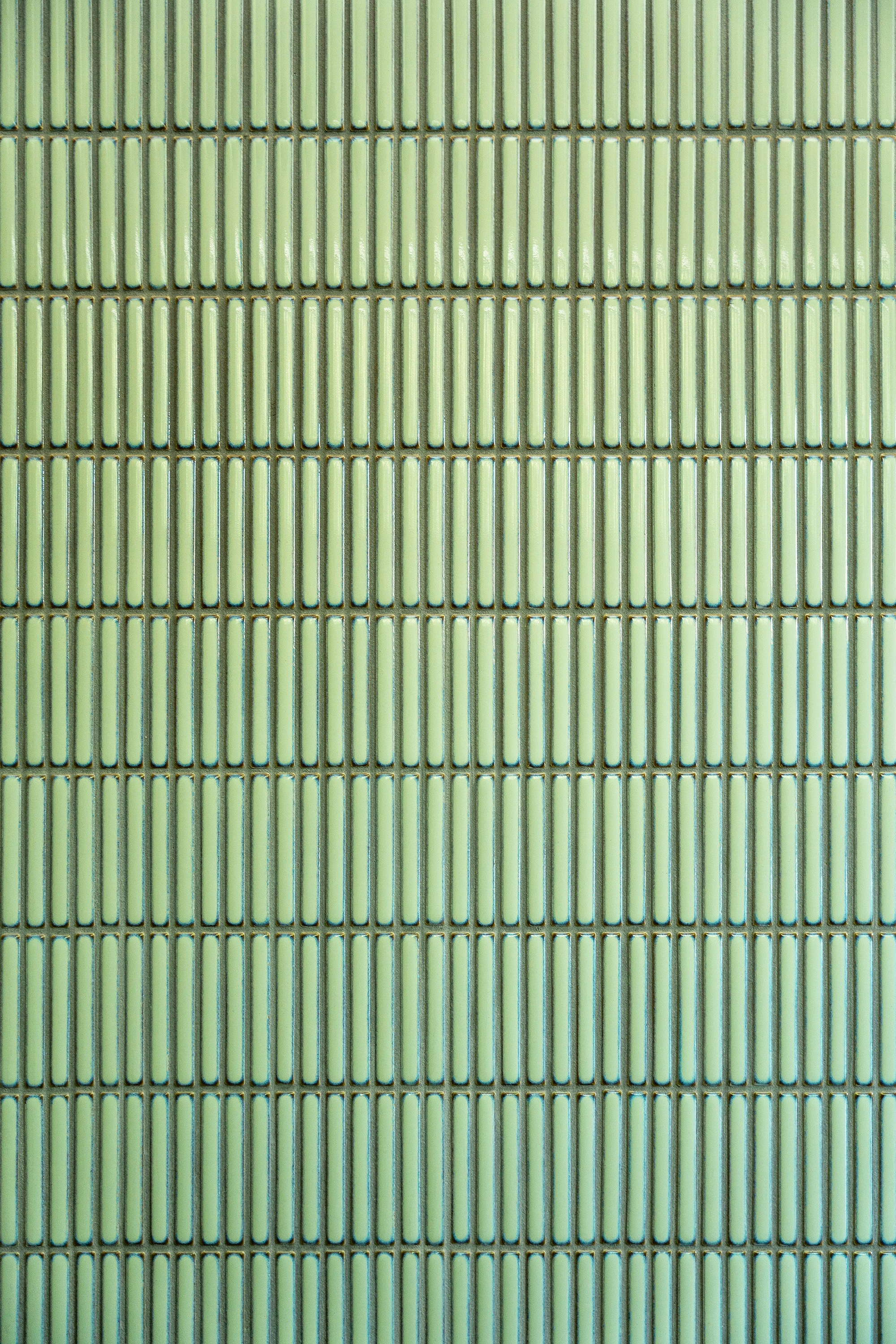 Detail shot of slender rectangular sage green tiles installed in bathroom shower
