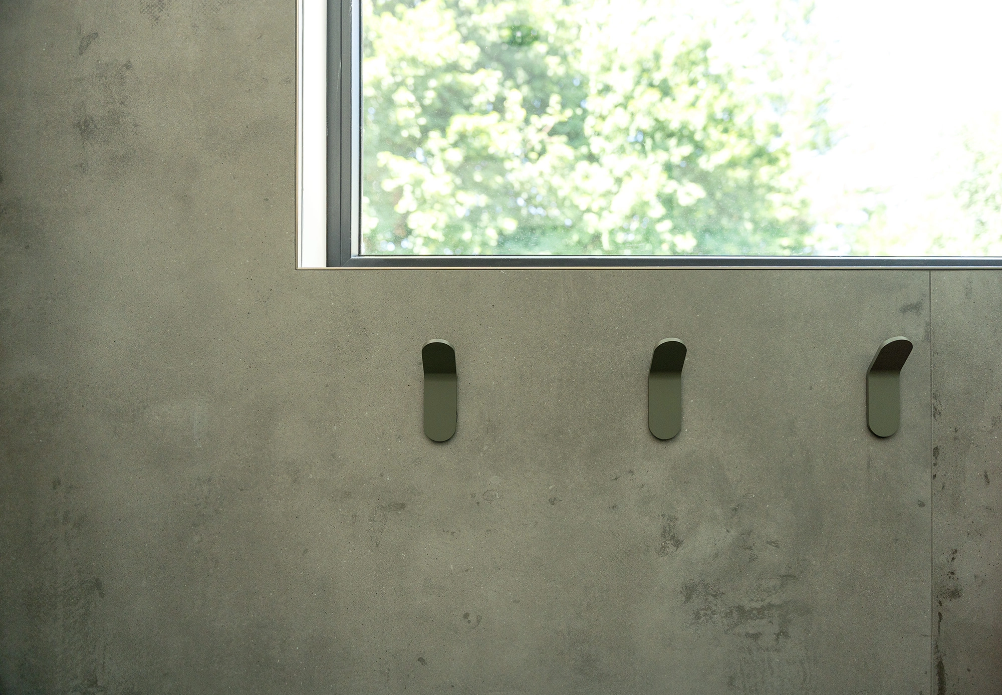 Exterior bathroom wall with stone finish, sleek rectangular window, and metal towel hooks