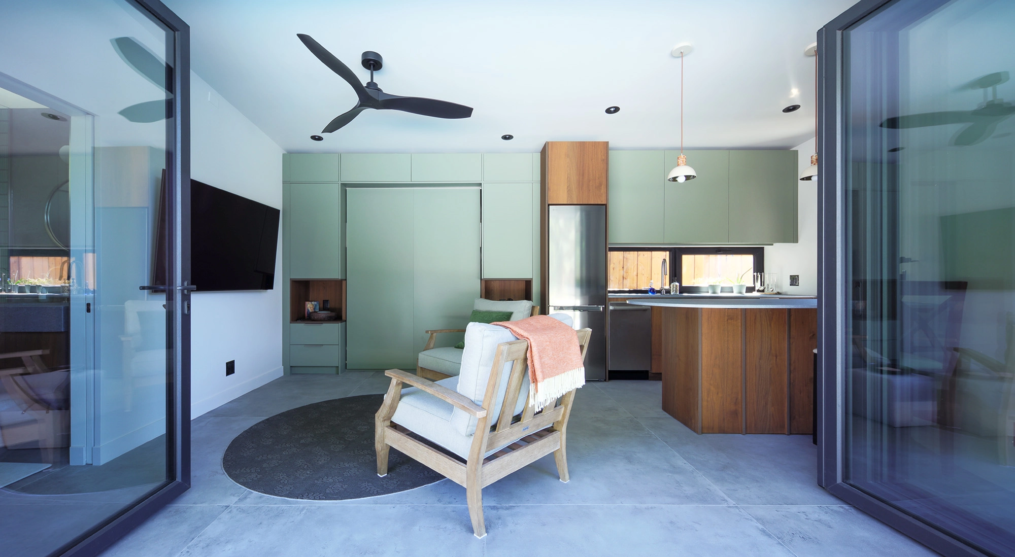Poolhouse interior showcasing wide open glass doors, a seating area, and kitchenette