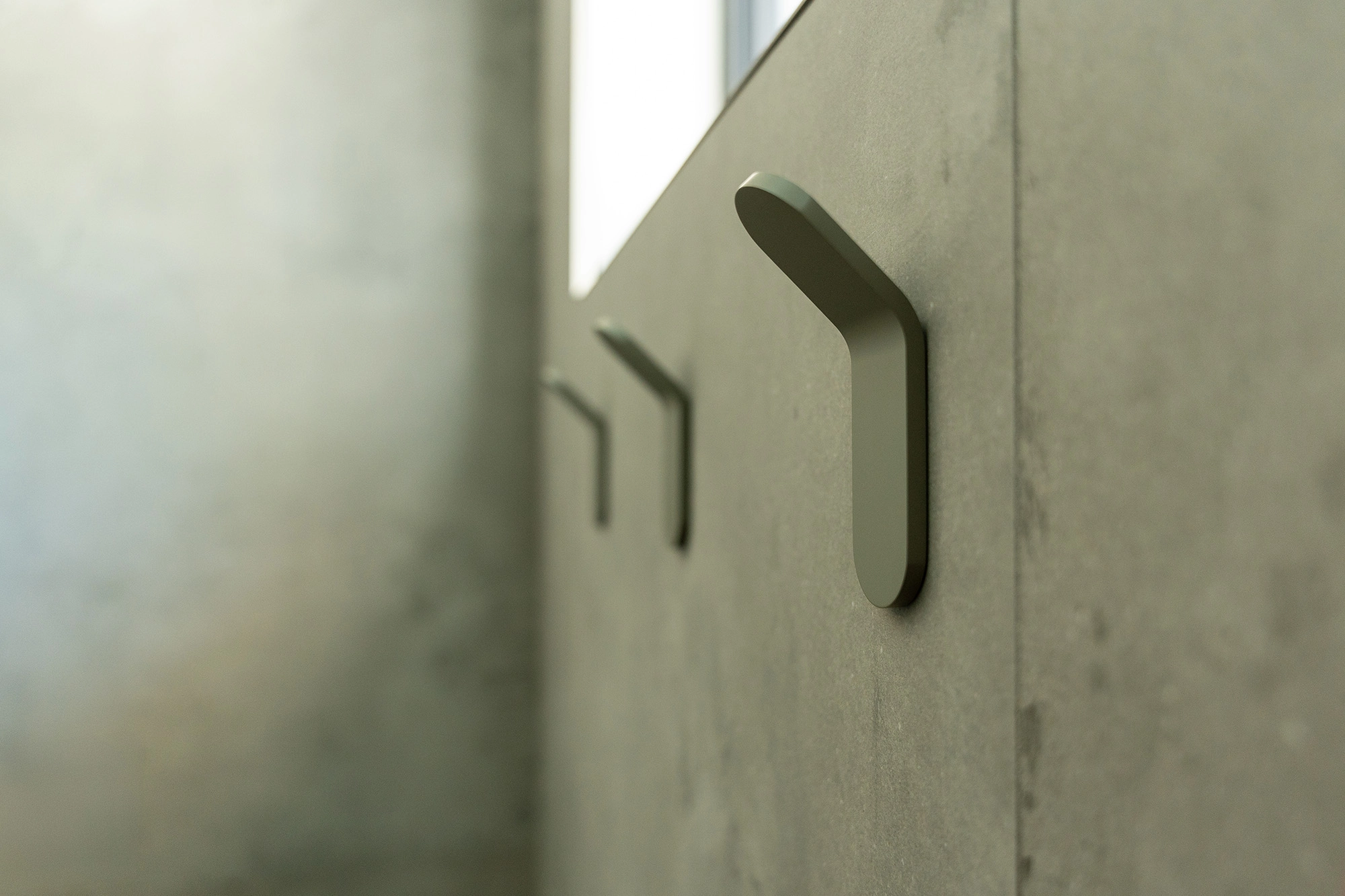 Close up of stone bathroom walls with sleek towel hooks installed on walls
