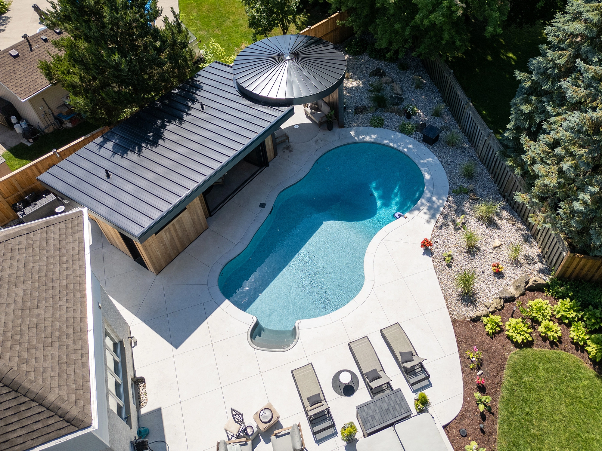 Aerial view of poolhouse structure, pool, and backyard
