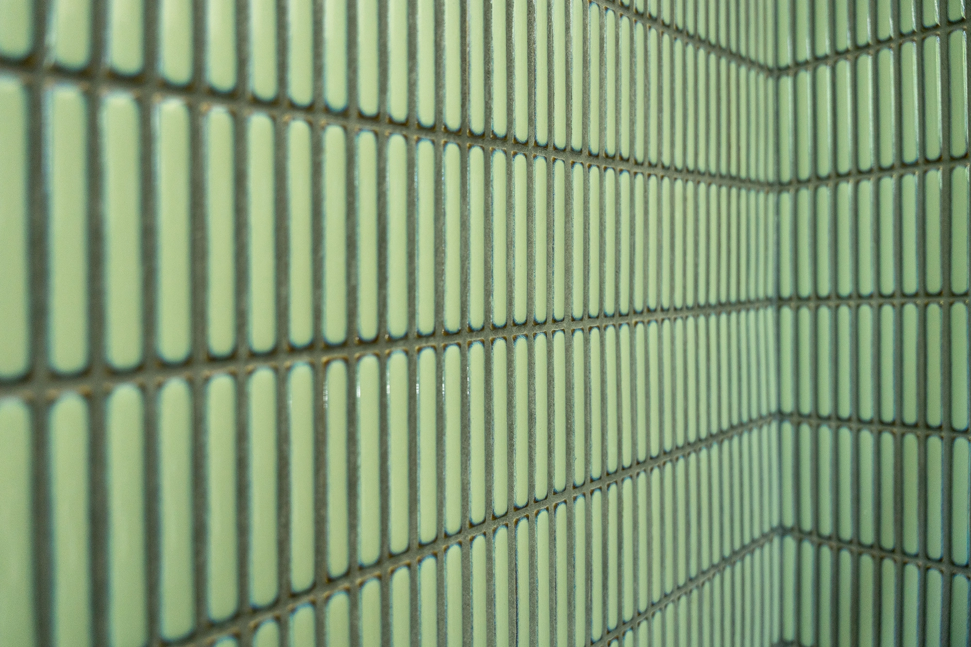 Close up details of sage green rectangular tiles installed in bathroom shower