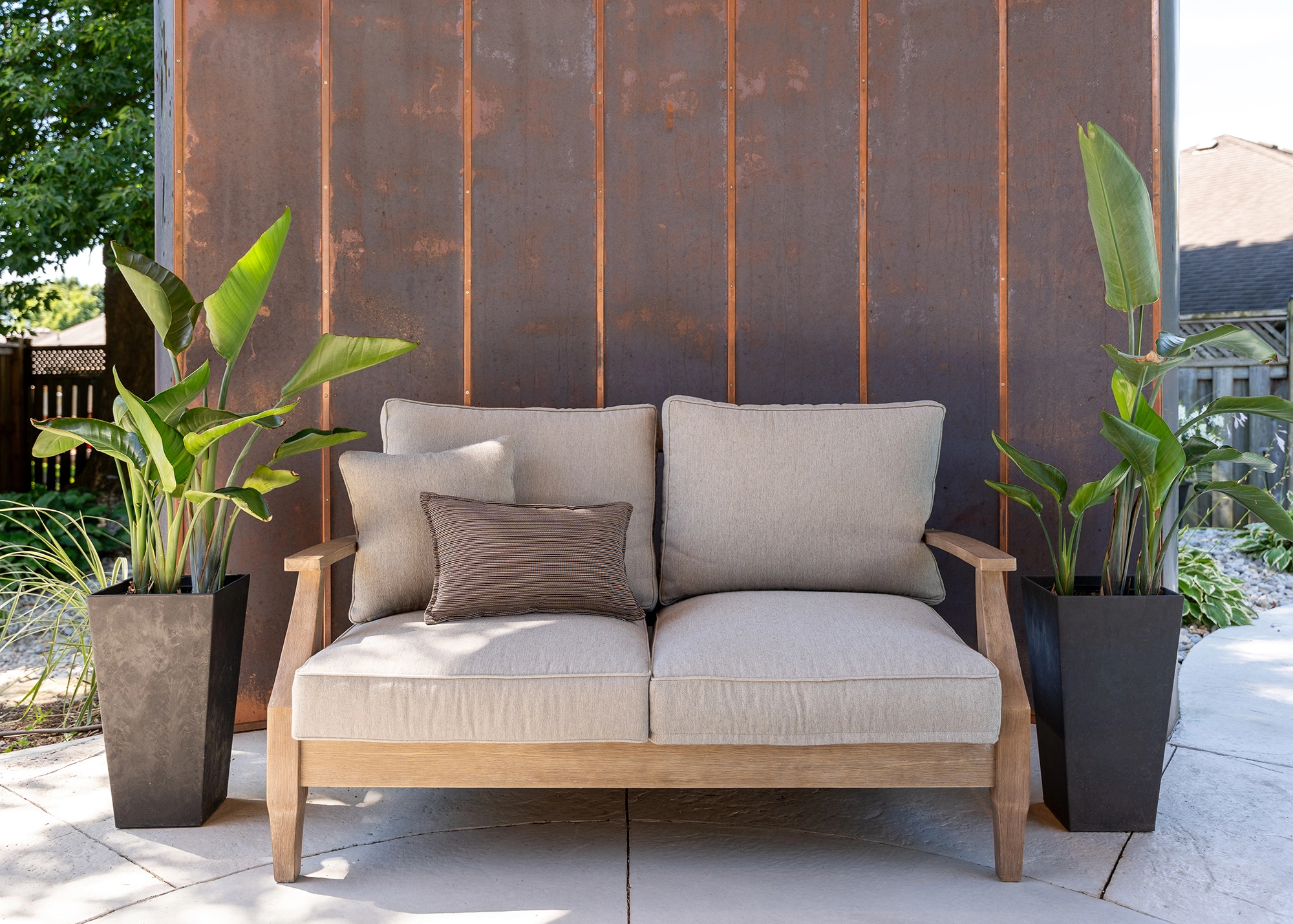 Cream coloured outdoor loveseat positioned in front of copper accent wall of open air rotunda
