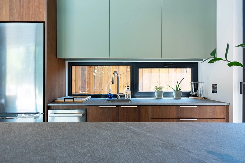 Poolhouse kitchenette with wooden and sage green cabinetry and stainless steel appliances