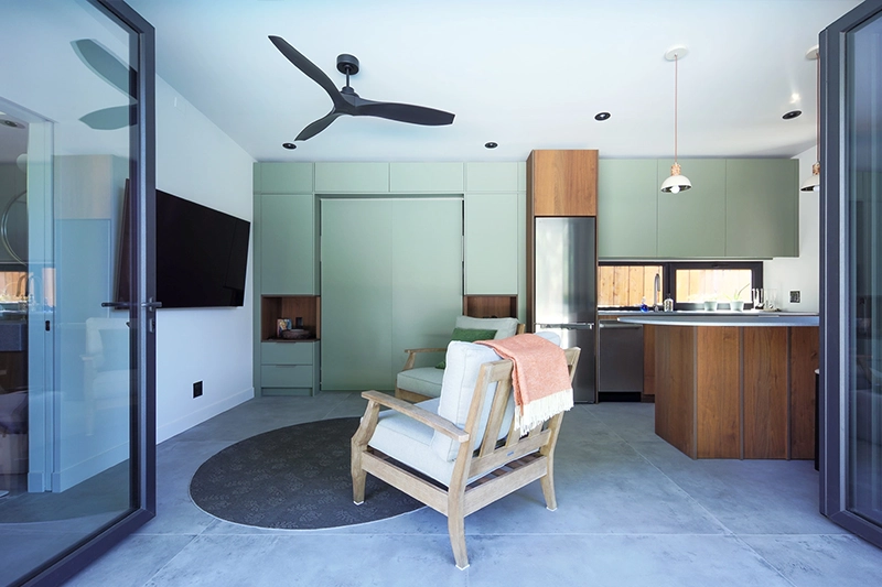 Poolhouse sitting area with beachy armchairs and green panelled walls in background
