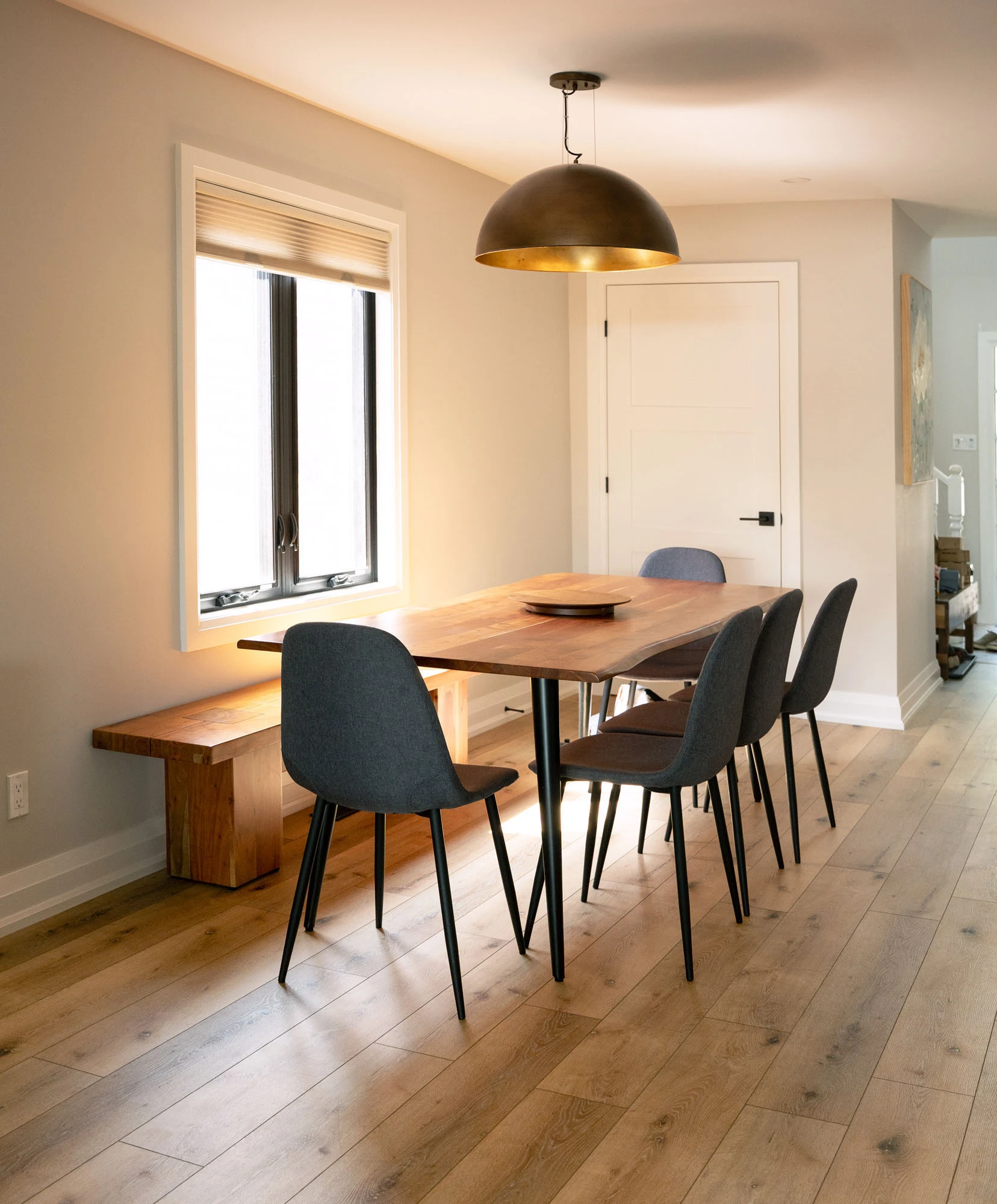 Dining area with wooden table and bench, overhanging pendant lamp