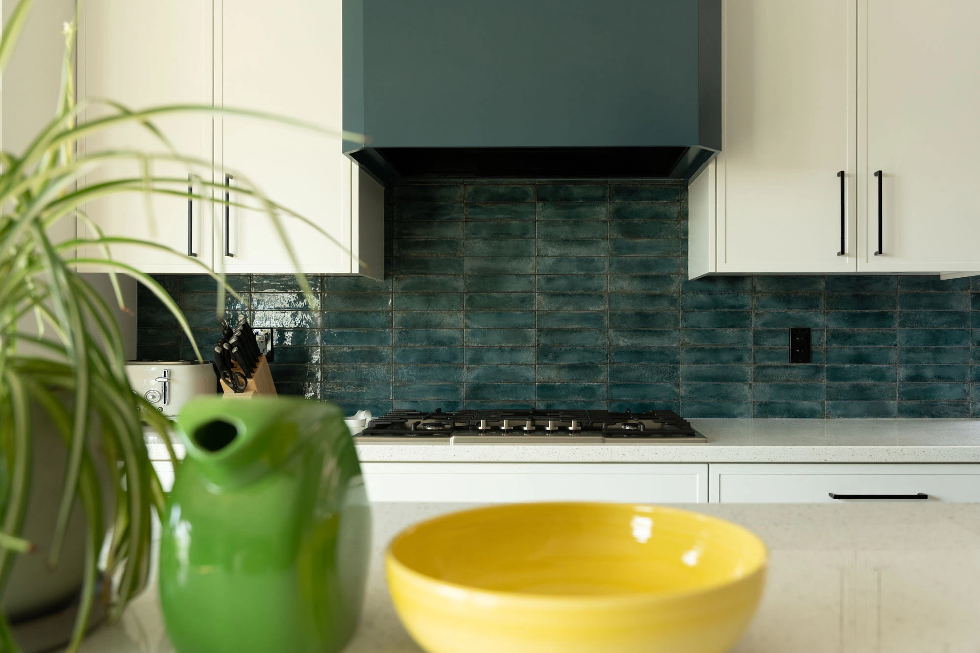 Colourful ceramic pots in foreground, white and blue kitchen cabinetry in background