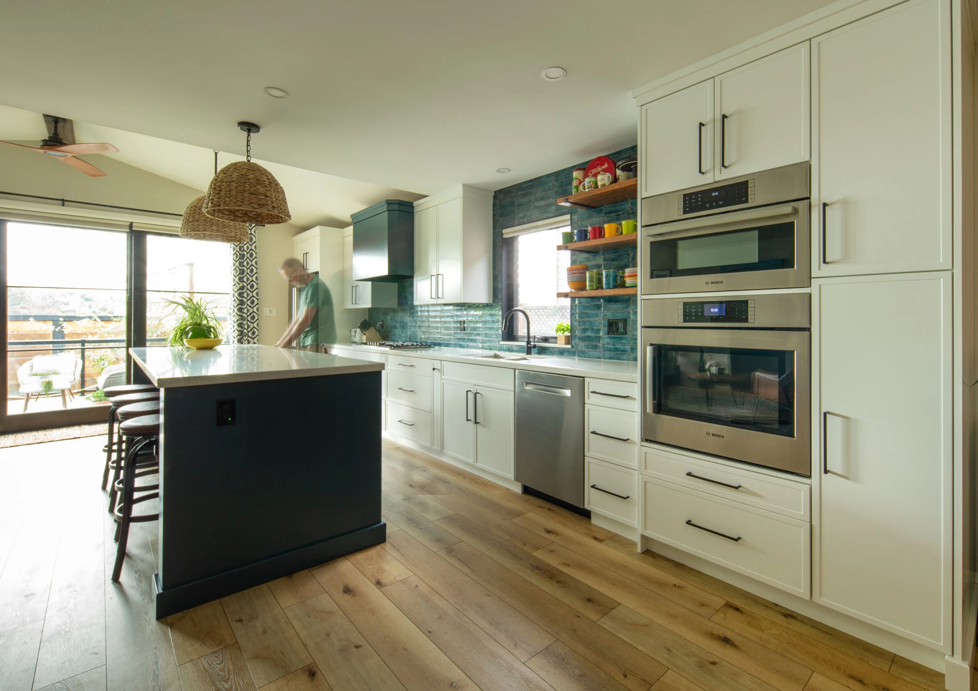 Homeowner standing at kitchen island, white and blue cabinetry and stainless steel appliances in background