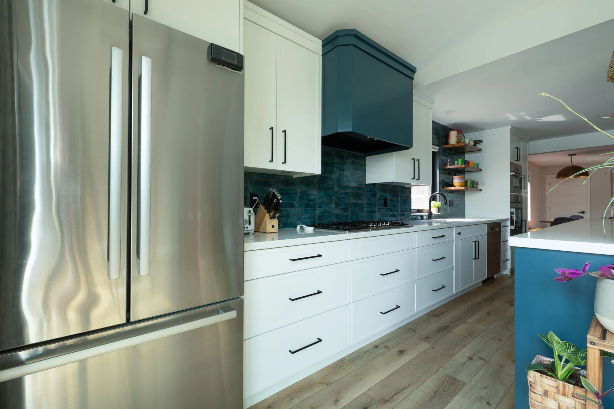 Stainless steel fridge, white kitchen cabinetry and hardwood floors