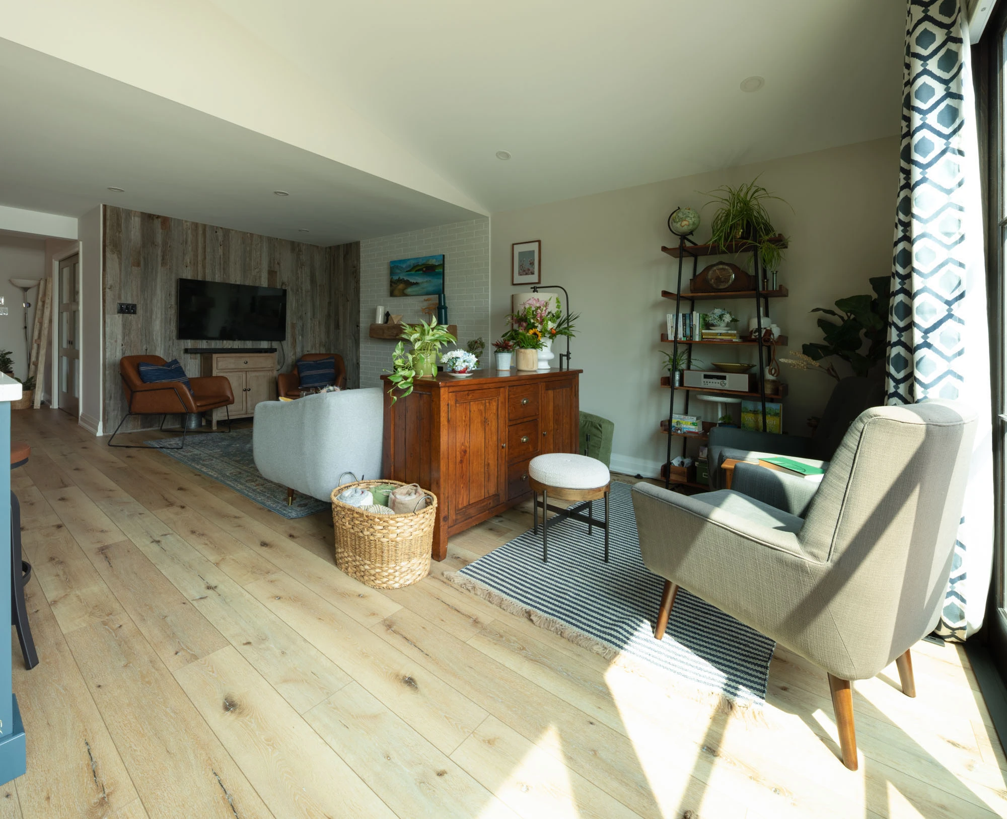 View of sitting area from far end, looking towards television, couch, and armchairs