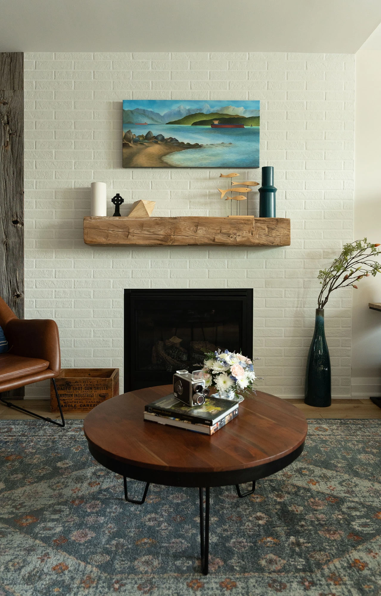 Sitting area fireplace with white painted brick wall, wooden mantle, and wood coffee table