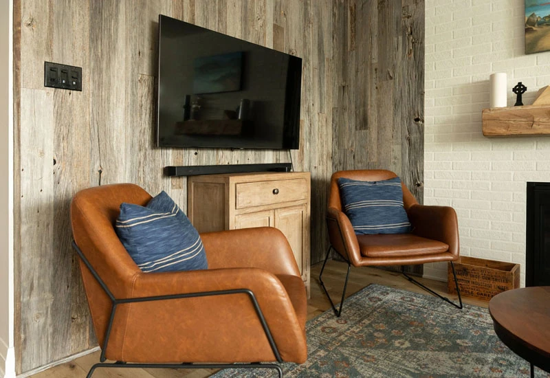 Two leather armchairs placed near wall-mounted television 