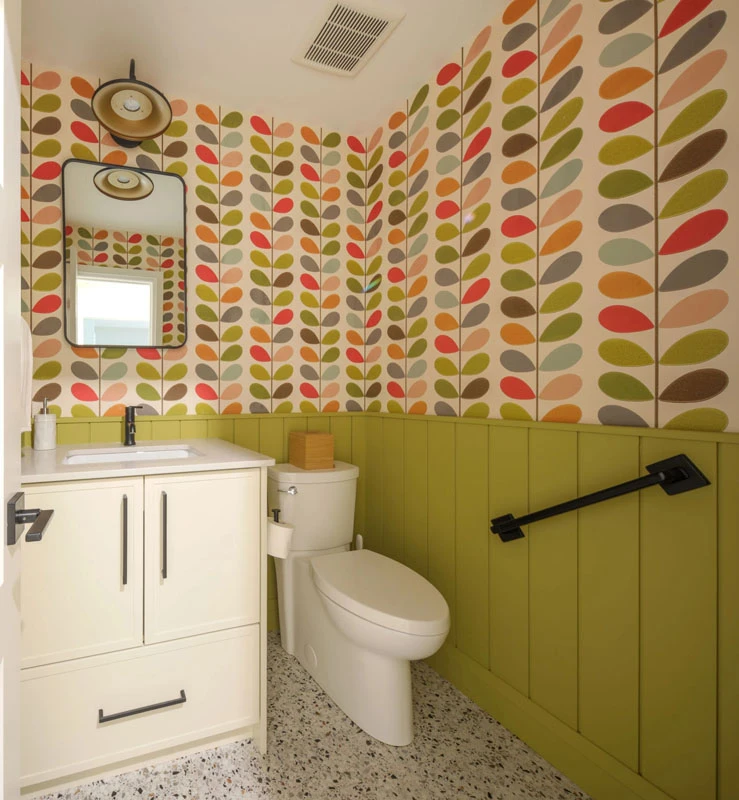 Powder room with brightly patterned wallpaper and lime green wainscoting