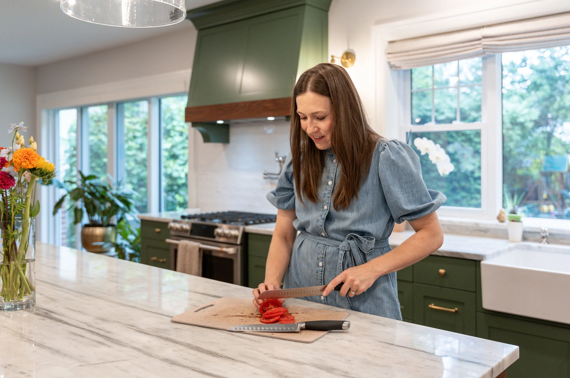 Smiling homeowner cutting a tomato on her granite kitchen island countertop