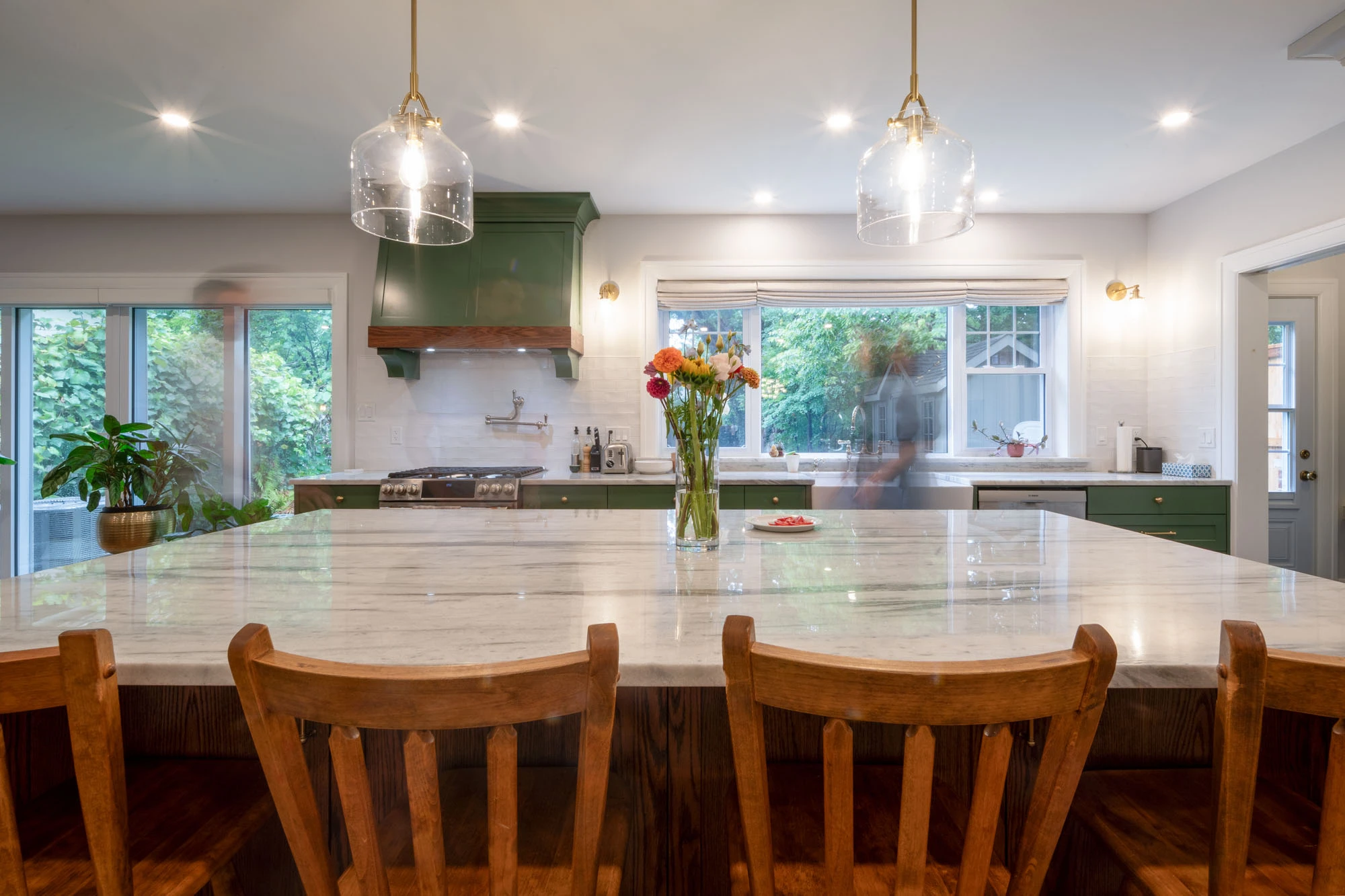 Brightly lit kitchen island with granite countertops and wooden stools lined up in front
