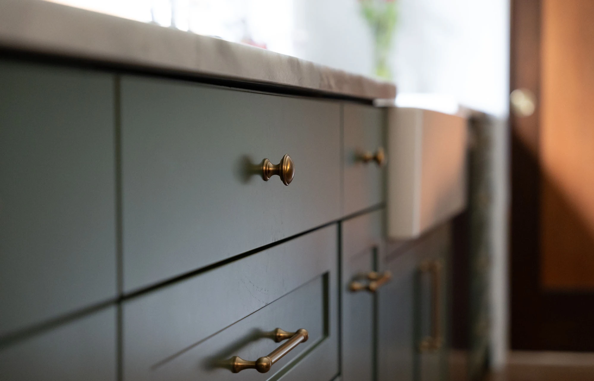Close up of green painted cabinetry with brass drawer pulls