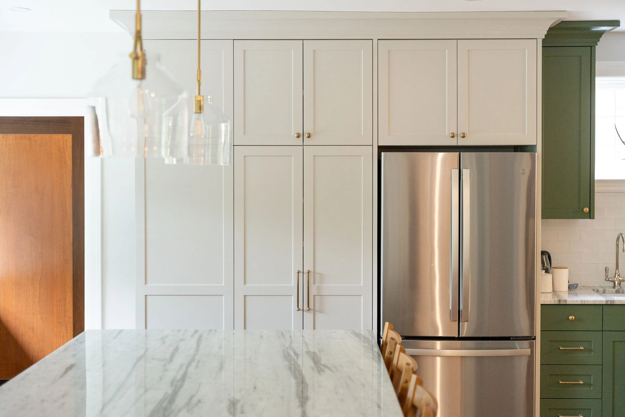 Wall of white kitchen cabinetry and stainless steel refrigerator