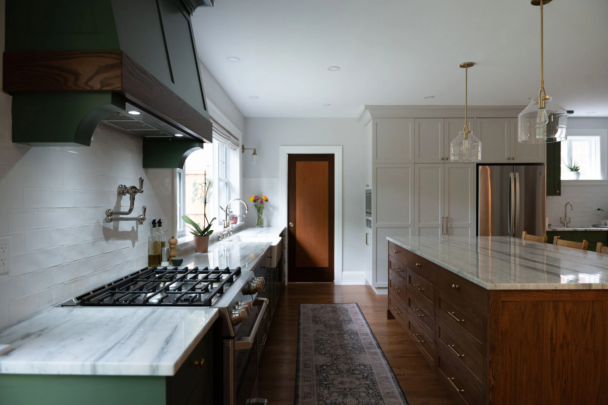 View of kitchen filled with natural light from picture window to highlight the stovetop, granite countertops, and solid wood kitchen island cabinetry. 