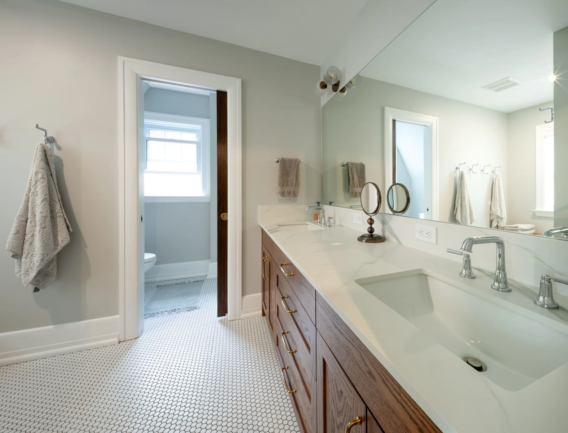 View of length of bathroom with solid wooden vanity, double sink, granite countertops, and separate water closet.