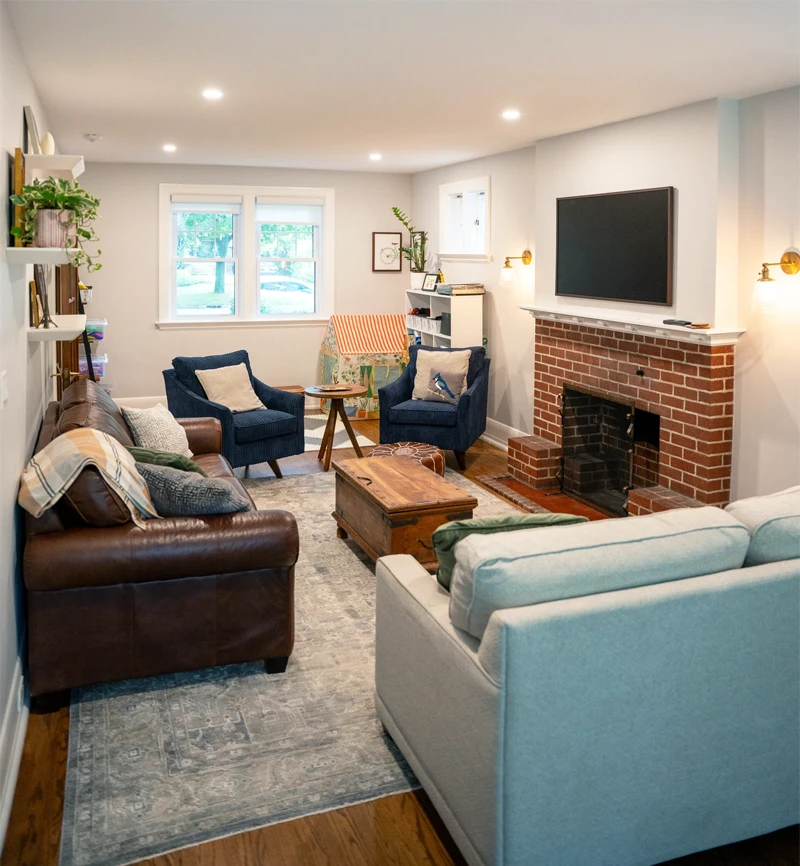 Brown leather couch positioned alongside sitting room wall with floating shelves above.