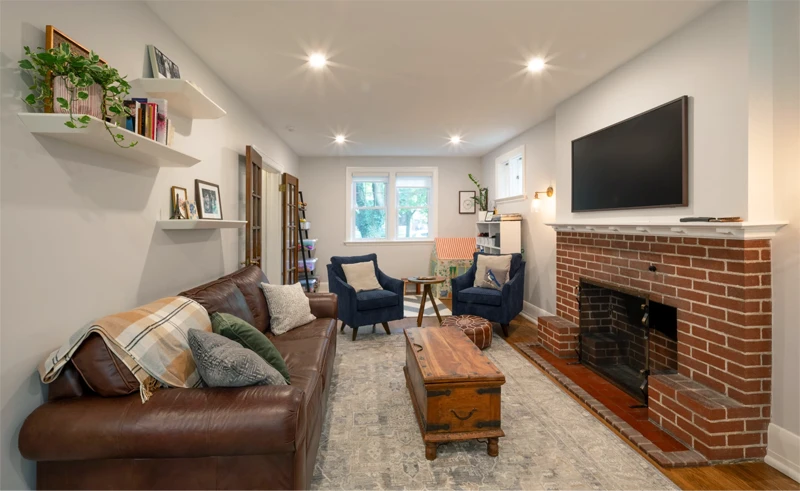 View of seating area with red brick fireplace, recessed lighting, and windows that let in natural light.