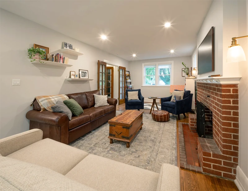 Sitting room area with couch, armchairs arranged in front of brick fireplace