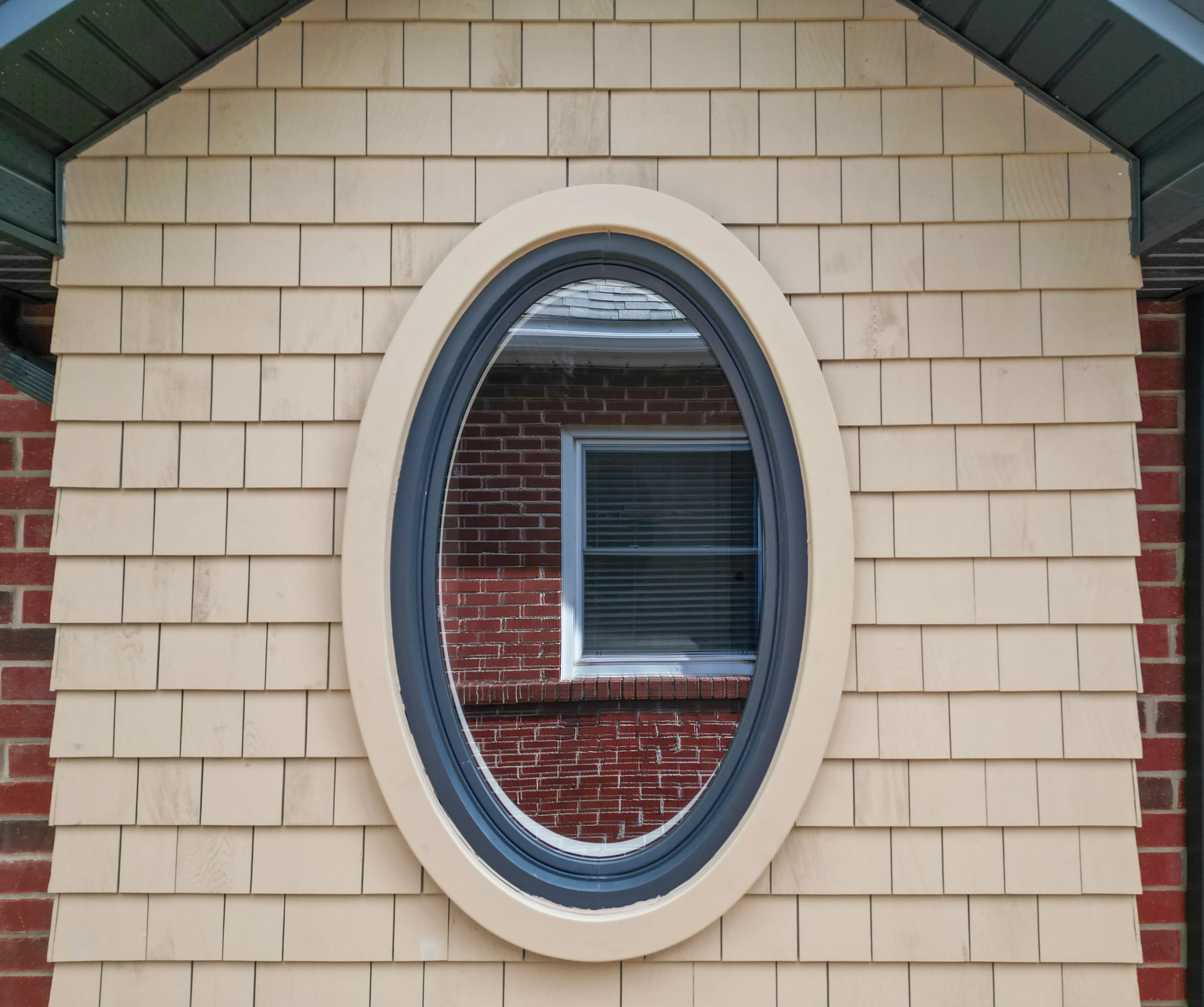 small window in the front of the house, oval shaped against cream brick