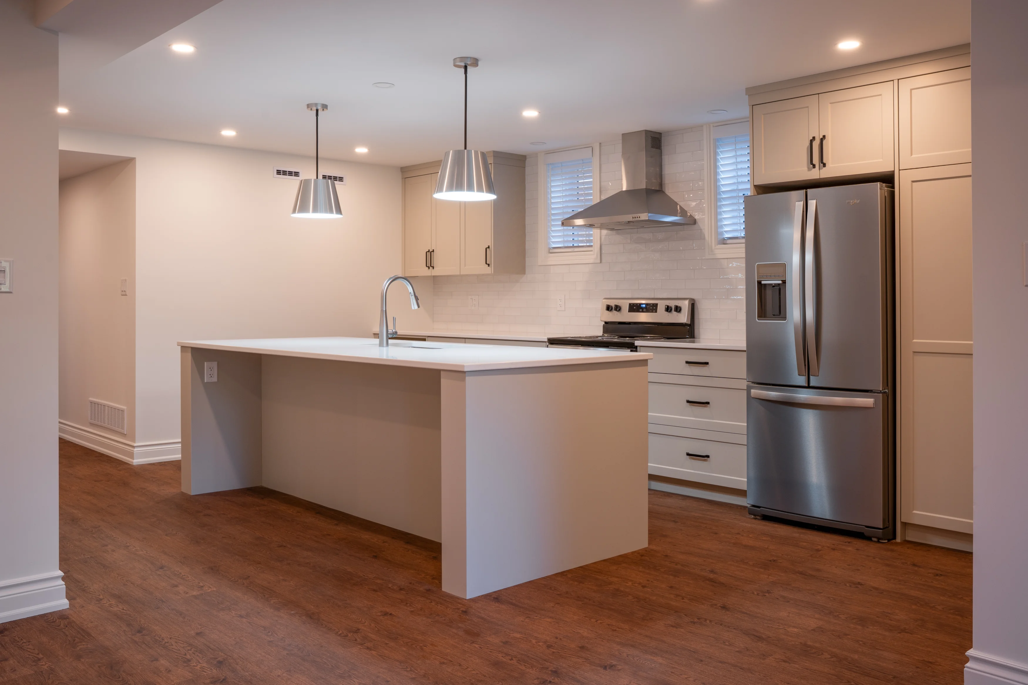 a large kitchen space in the basement with fridge, counters, and lots of floor space