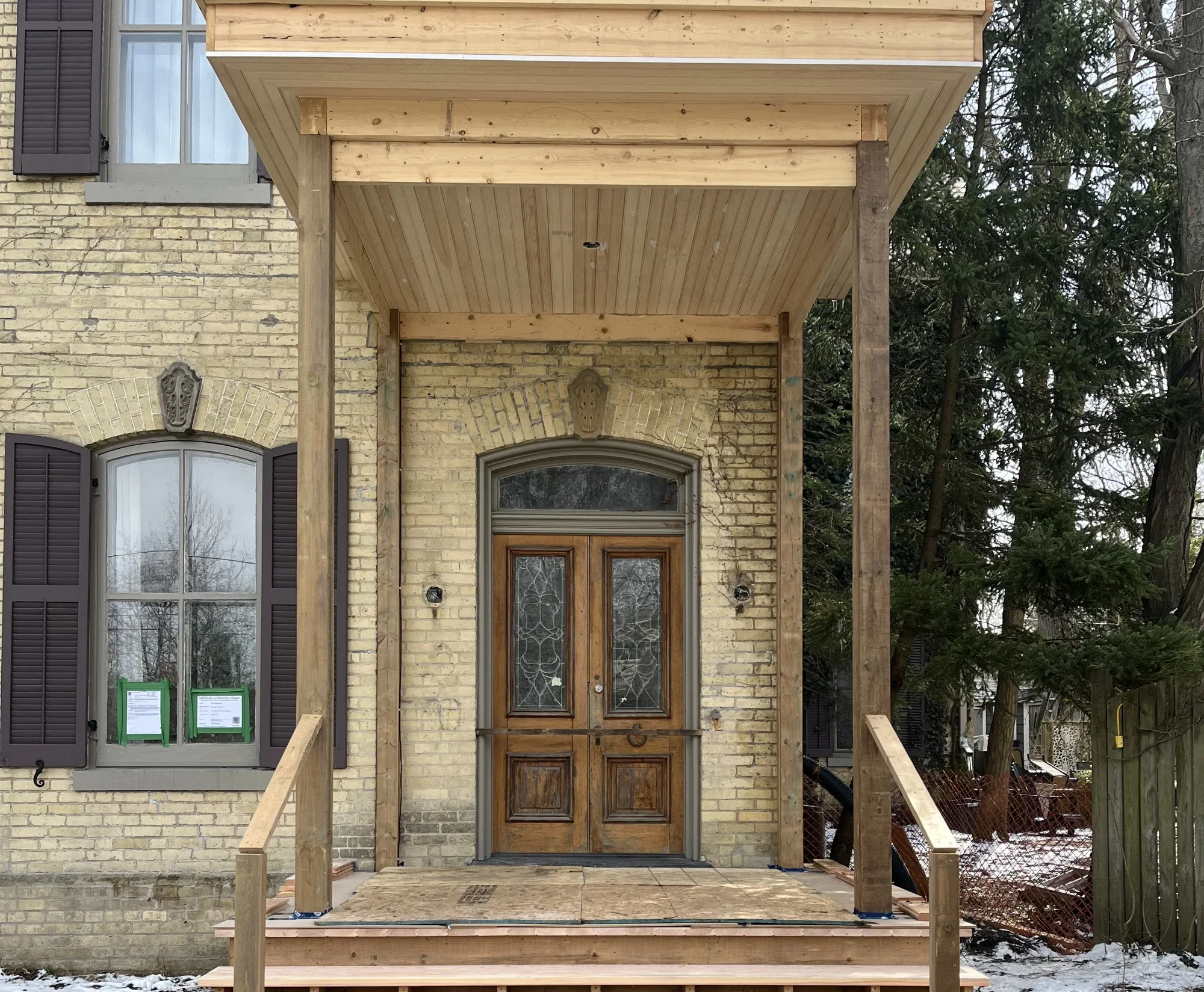 Exterior of heritage home during construction with front deck being constructed