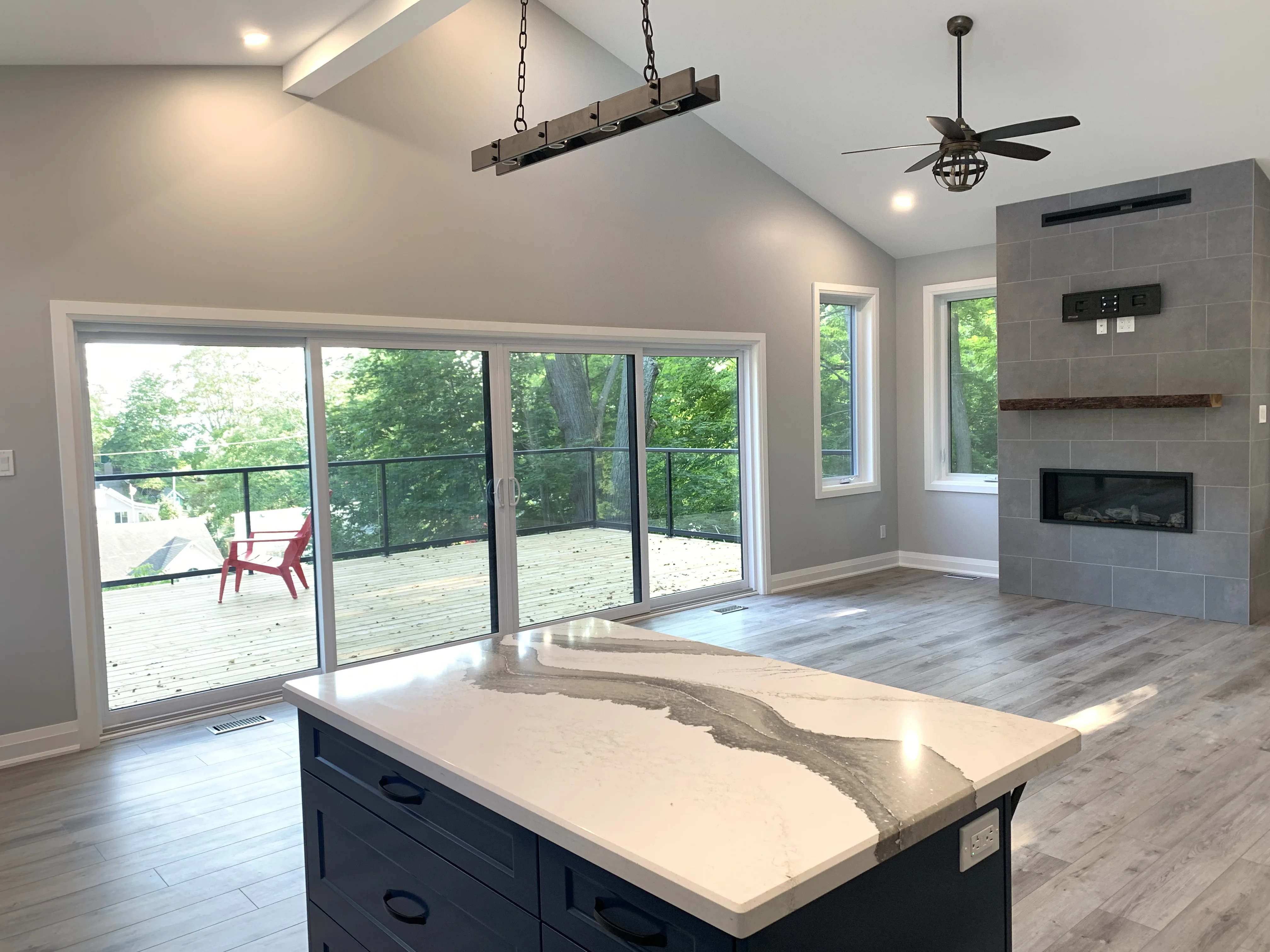 facing the living area of cottage near a fireplace and counter with windows facing rear of lot