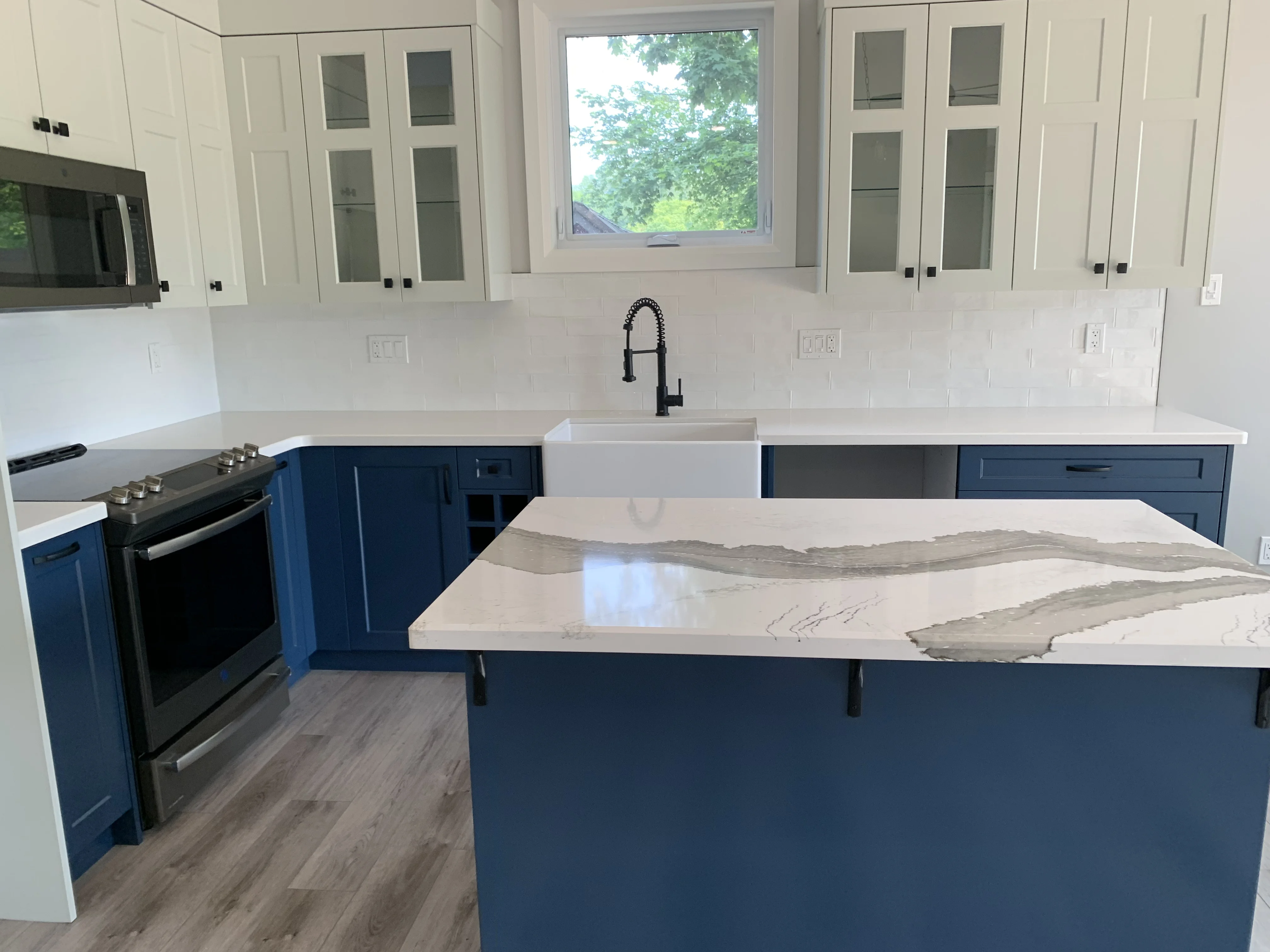 white cupboards over a marble counter and blue cabinets