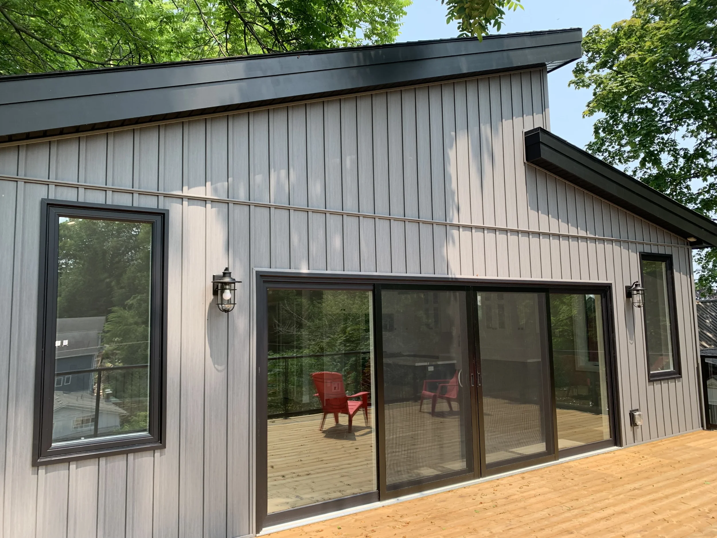 rear exterior of cottage with large glass windows and doors facing a deck