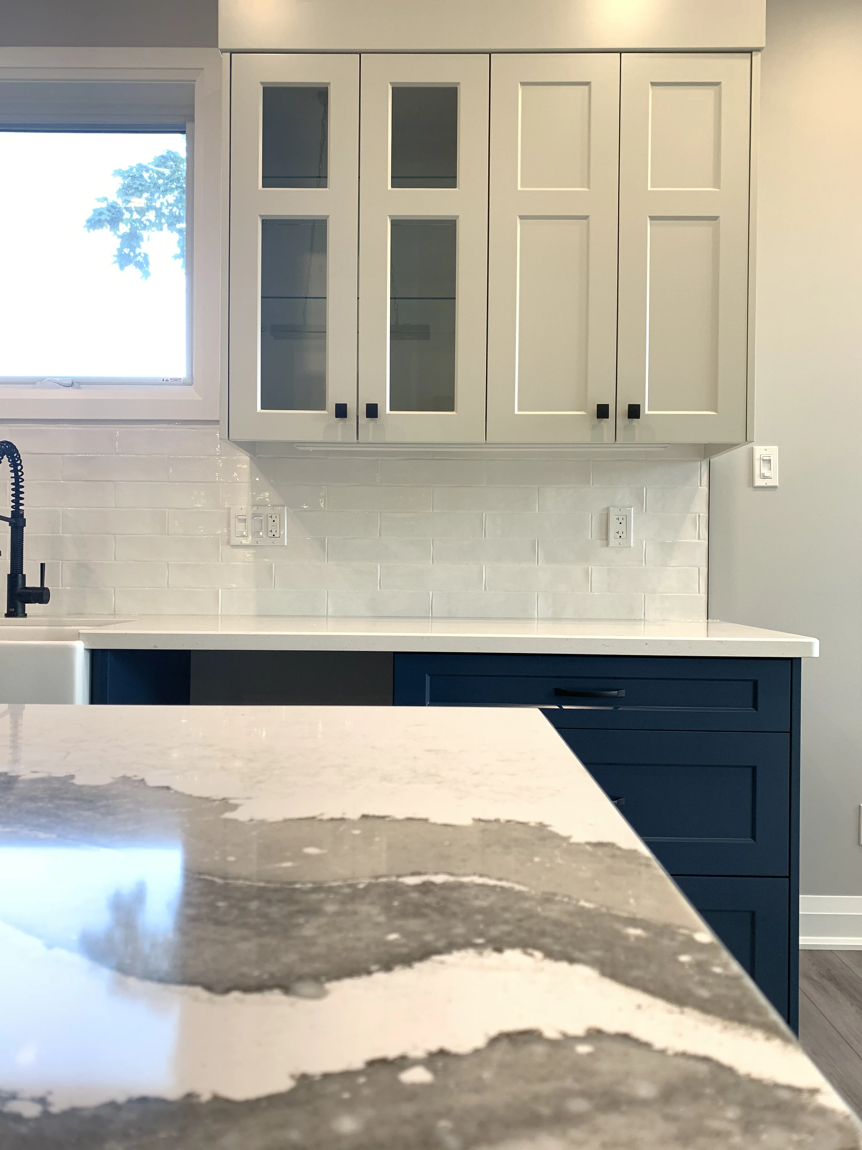 white cupboards over a marble counter and blue cabinets