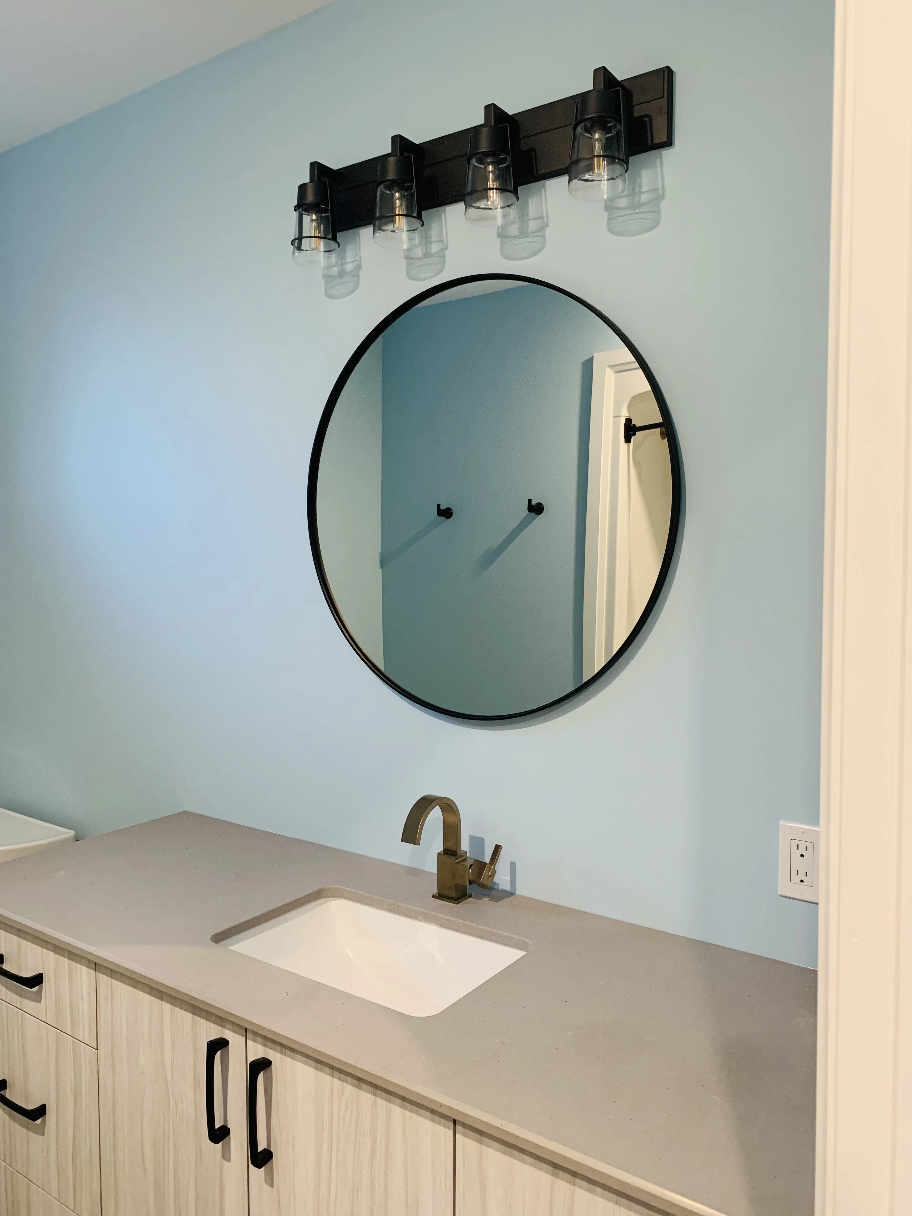 white sink and grey counters with a mirror overtop