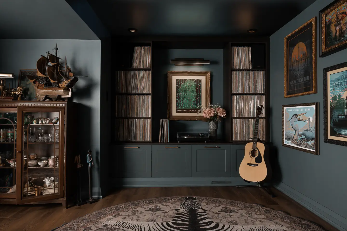 a large wall unit for records and an acoustic guitar