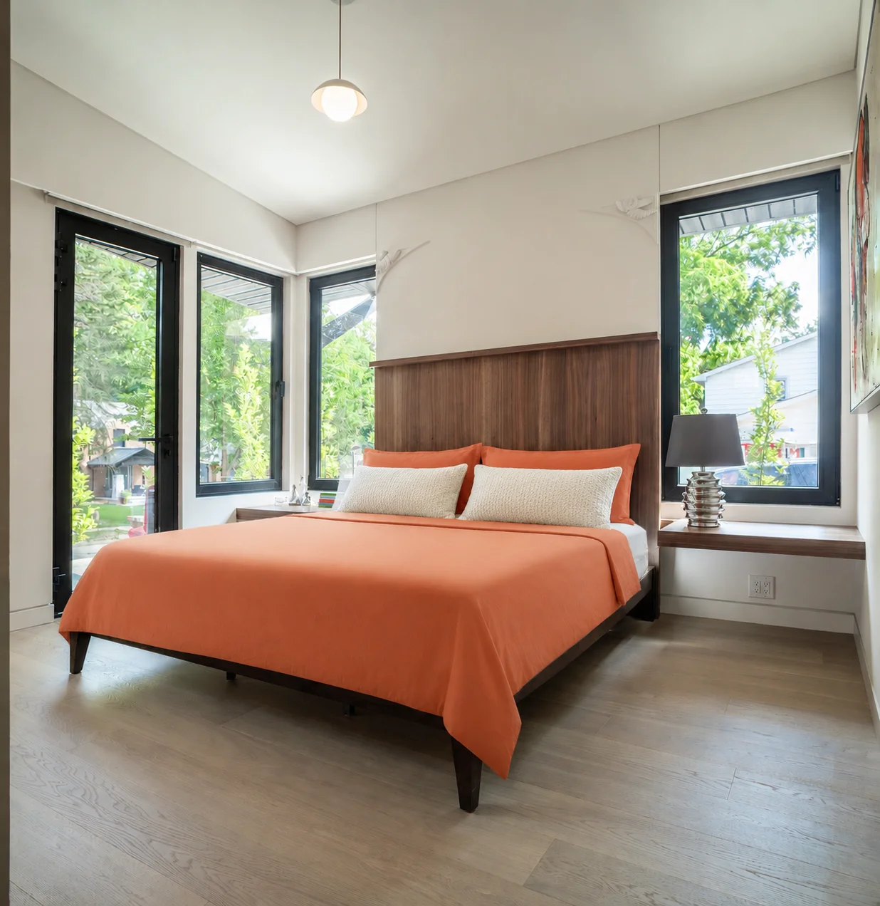 large bed with wooden headboard and large windows